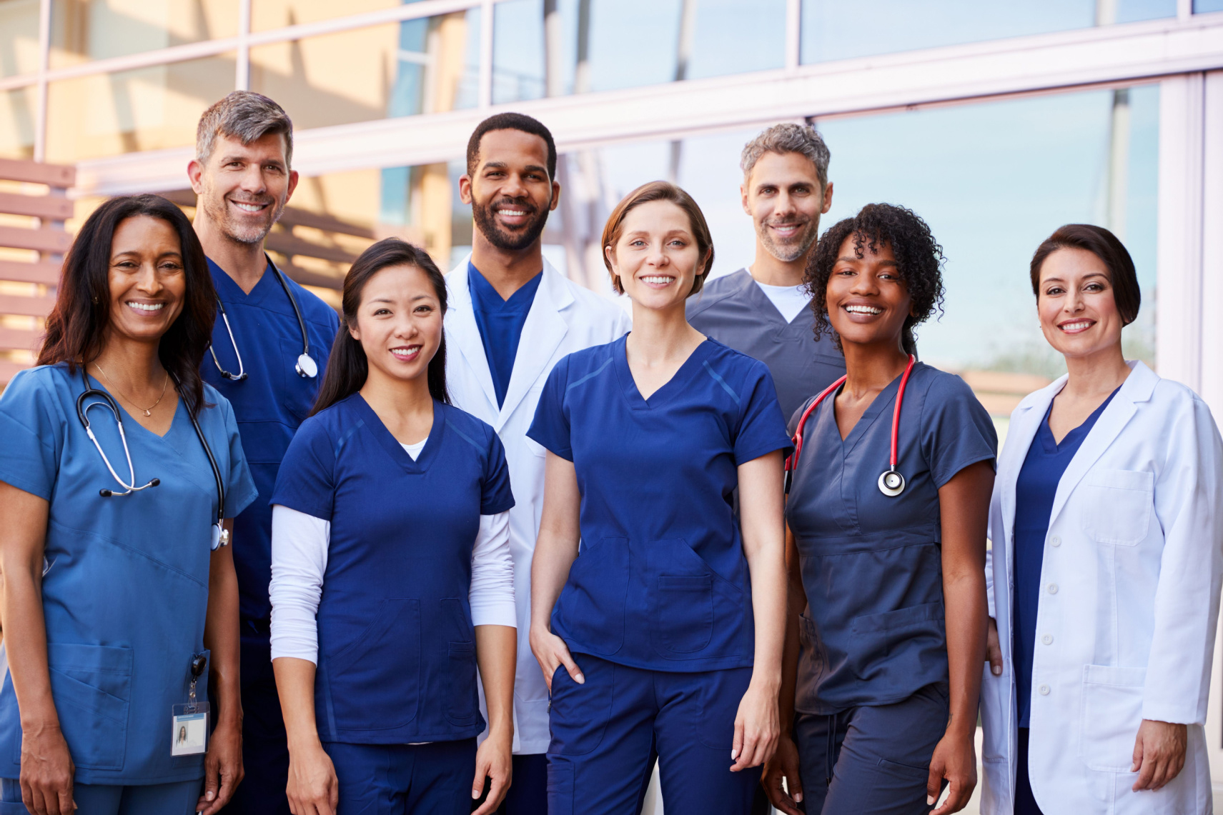 Smiling healthcare team standing outside a hospital