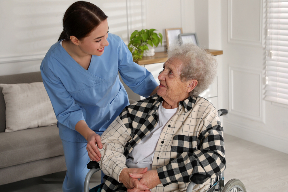 Nurse assisting woman in a wheelchair in her home.